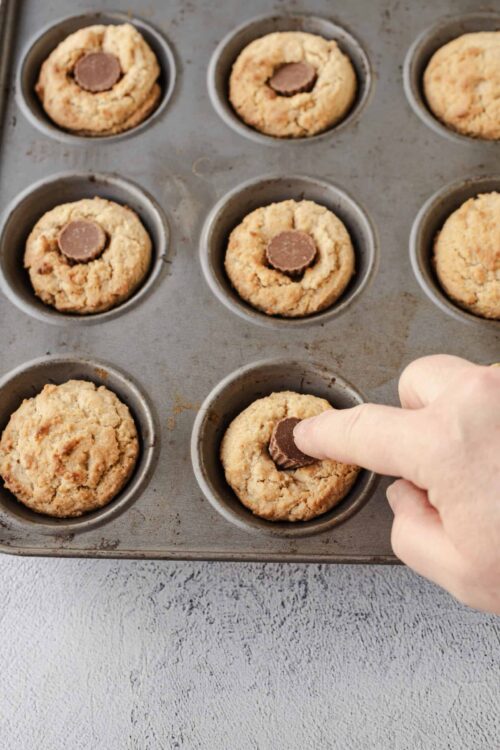 Butter cookies with chocolate center in mini muffin tin during baking process.