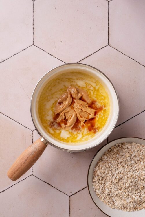 Creamy peanut butter, honey, and oats in a saucepan for homemade oatmeal cookies.