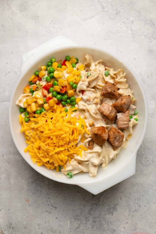 Creamy chicken and vegetable pasta casserole with shredded cheddar cheese, peas, corn, and tender chicken bites.