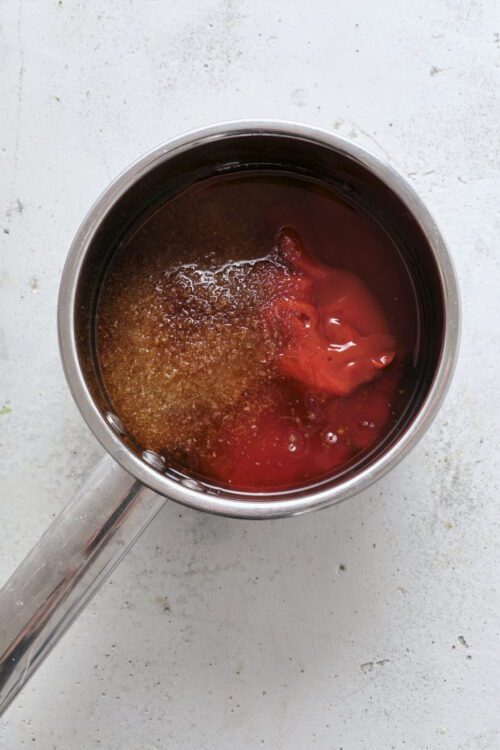 Sweetened cherry pie filling boiling in a stainless steel pot.