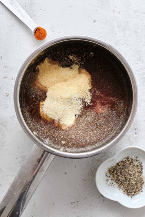 Sweet BBQ sauce ingredients in a saucepan with pepper and spices.