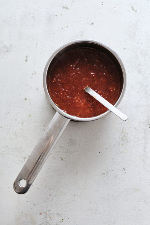 Rich homemade barbecue sauce in a stainless steel saucepan.