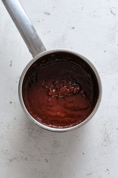 Rich chocolate sauce in a metal saucepan, perfect for baking and dessert recipes.