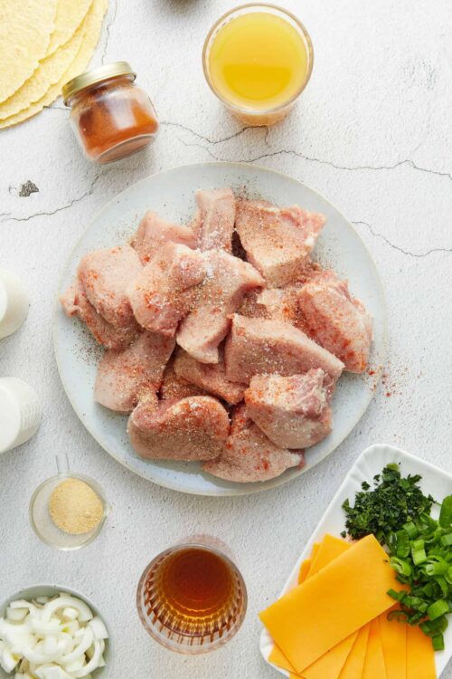 Fresh chicken drumsticks seasoned with spices for baking or roasting, with ingredients and seasonings arranged around.