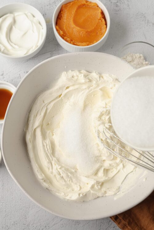 Cream cheese and sugar in a mixing bowl, ready for making cheesecake.