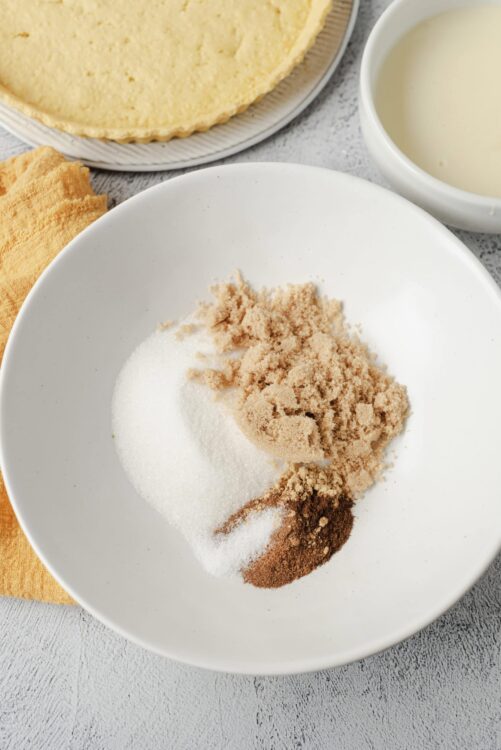 Flour, sugar, brown sugar, and cocoa powder in a white bowl for baking desserts.