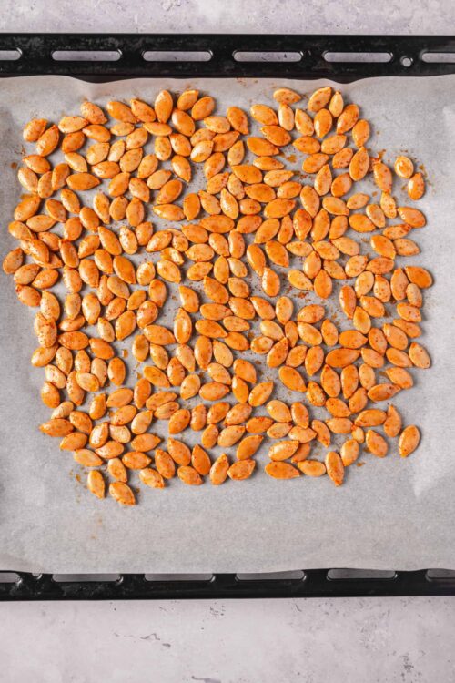 Roasted salted pumpkin seeds on parchment paper for baking or snack.