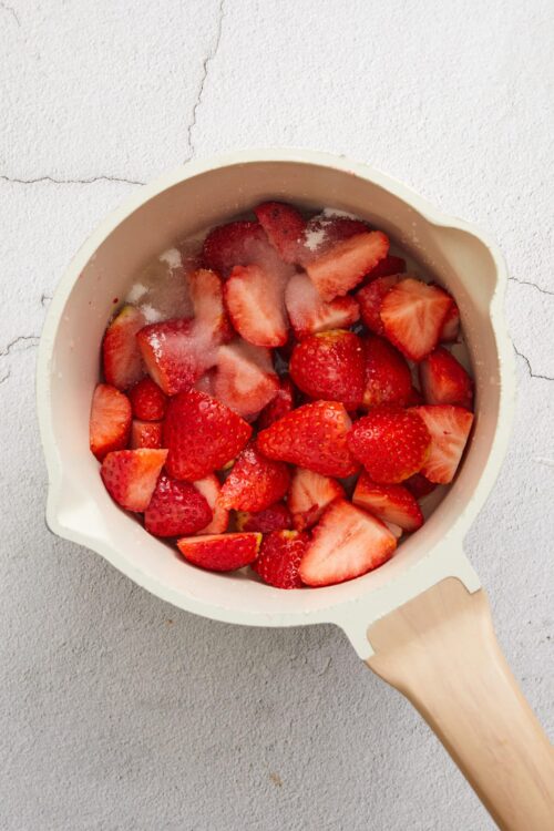 Fresh sliced strawberries in a white bowl for baking or dessert recipes.
