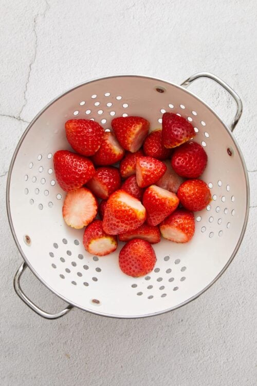 Fresh strawberries in a stainless steel colander.