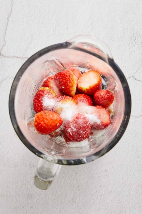 Fresh strawberries with sugar in a blender for strawberry dessert recipe.
