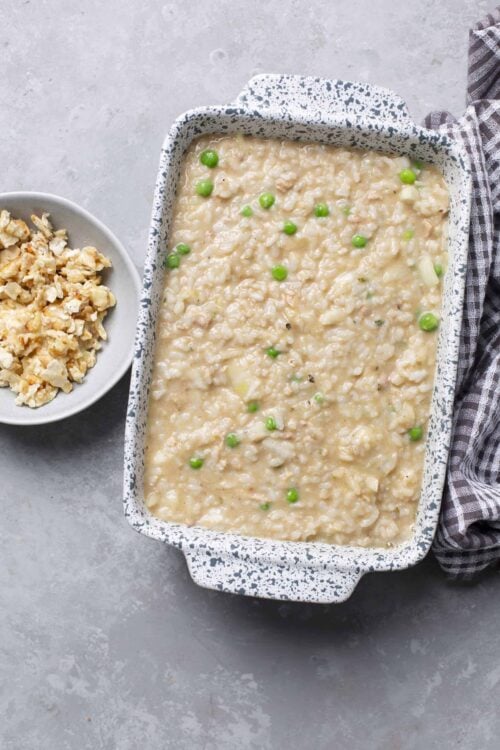 Creamy chicken and rice casserole with peas in a speckled baking dish.