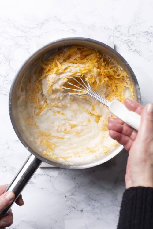 Creamy cheese and milk mixture in a saucepan for homemade mac and cheese.
