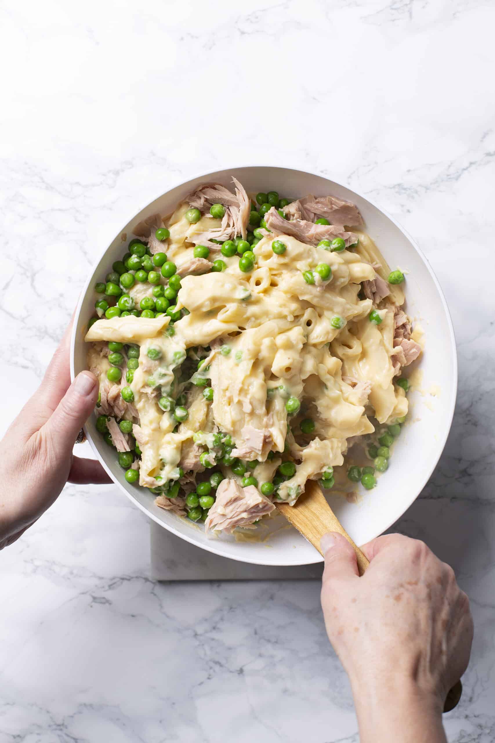 Savory chicken and green pea casserole in a white bowl on marble surface.