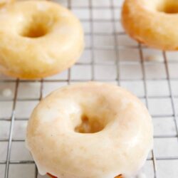 Creamy glazed donuts cooling on a wire rack, fresh and delicious.