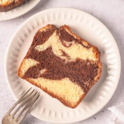 Marbled vanilla and chocolate pound cake on white plate with fork.