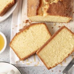 Fluffy homemade vanilla pound cake sliced on a wooden board with a crusty golden exterior.