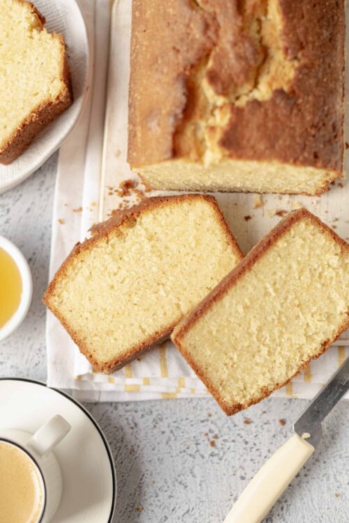 Fluffy homemade vanilla pound cake sliced on a wooden board with a crusty golden exterior.