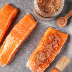 Salmon fillets with seasoning and herbs, ready for cooking or baking.