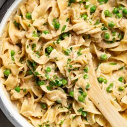Creamy chicken and pea tortellini in a skillet, garnished with fresh herbs, perfect for cozy family dinners.