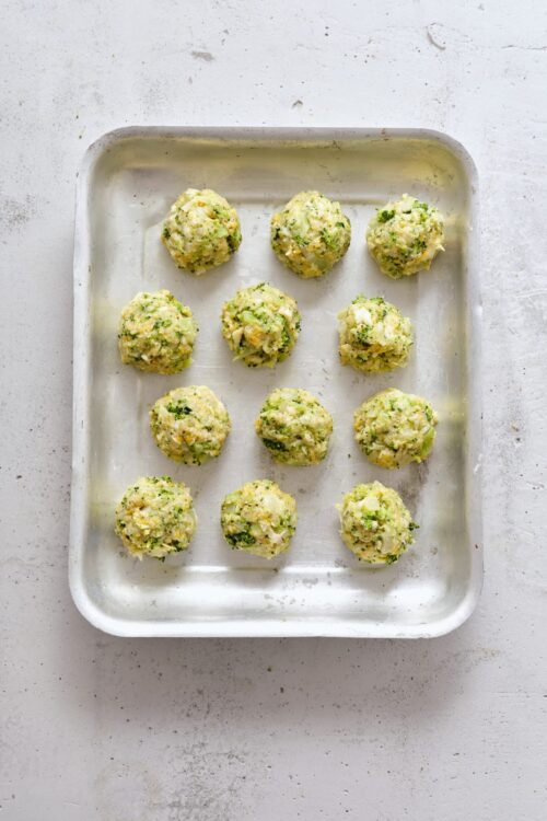 Creamy broccoli cheese dumplings on baking sheet.