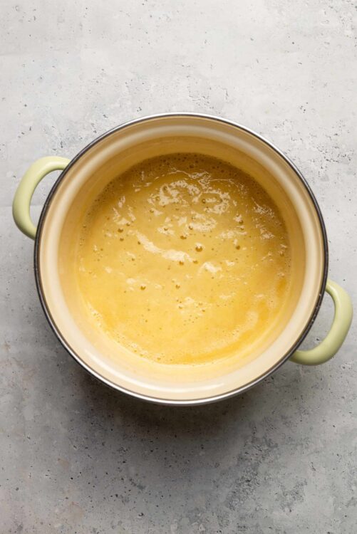 Creamy homemade custard in a yellow ceramic bowl on gray surface.