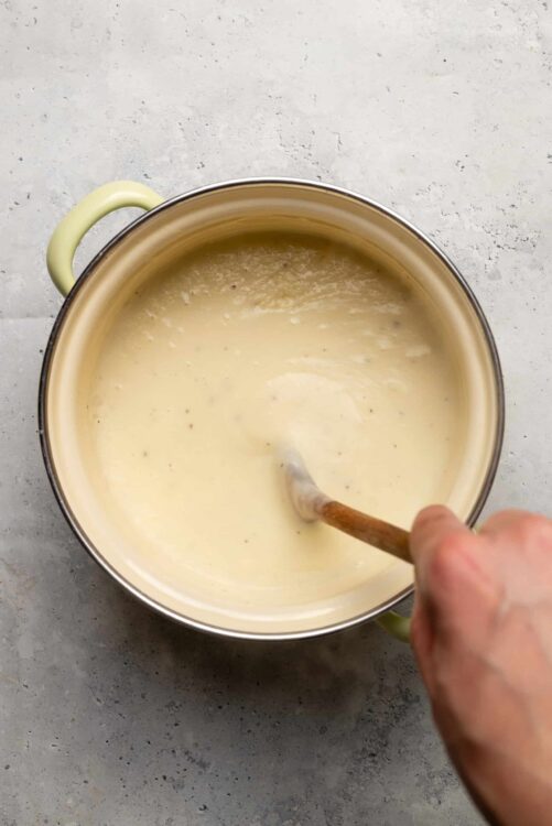Creamy cheese sauce in a pot for baking recipes or cheesy dishes.