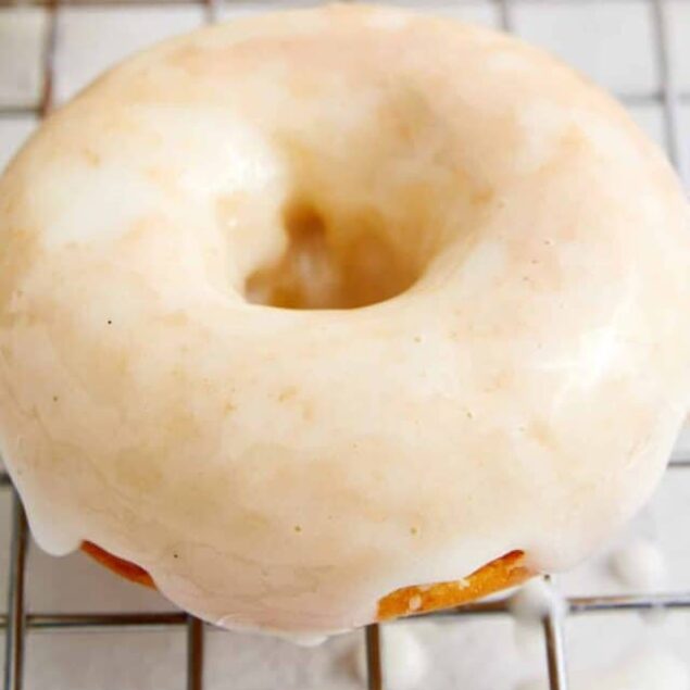 Creamy glazed donuts cooling on a wire rack, fresh and delicious.