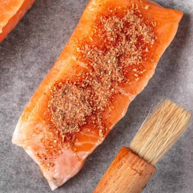 Salmon fillets with seasoning and herbs, ready for cooking or baking.