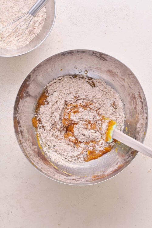 Flour, sugar, and eggs being mixed for homemade baking on a light countertop.