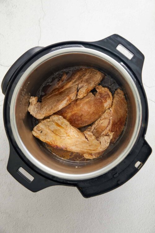 Slow cooker beef brisket cooking in an instant pot for flavorful, tender meat recipe.