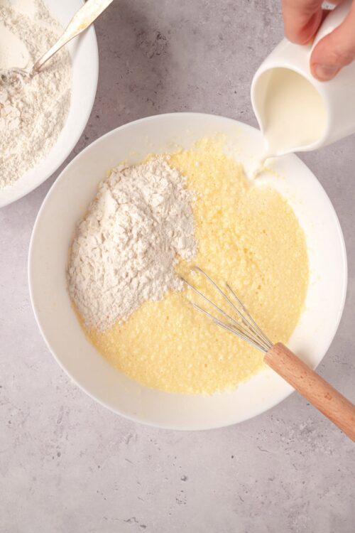 Flour and milk being combined in a mixing bowl for baking dessert or bread recipe.