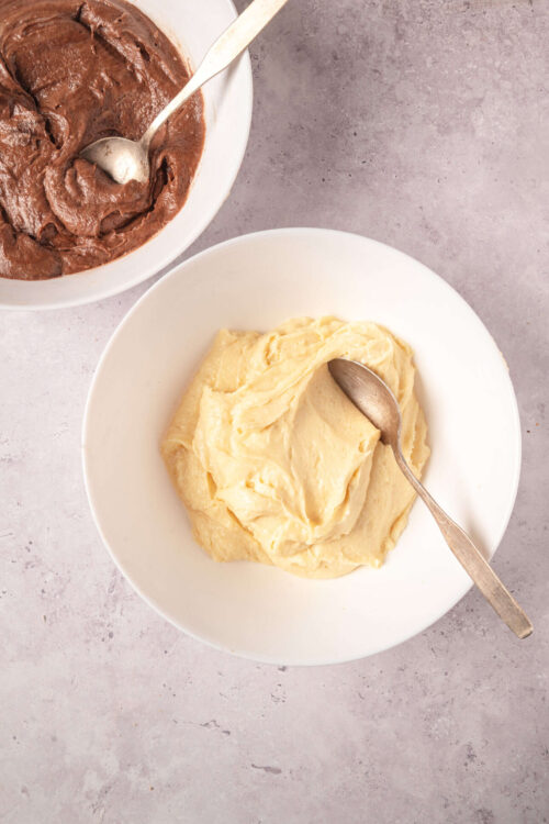 Creamy vanilla and rich chocolate frosting in white bowls, perfect for baking or decorating cakes.