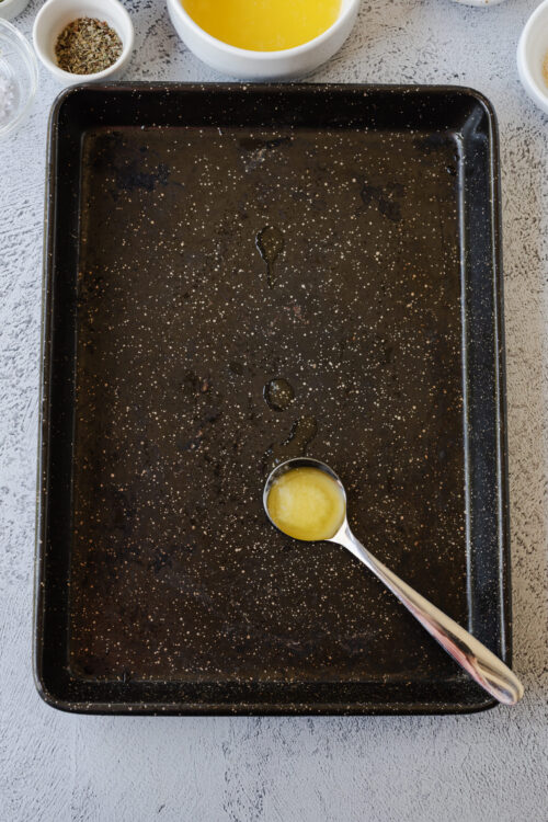 Buttered baking sheet with olive oil residue and tiny splatters.