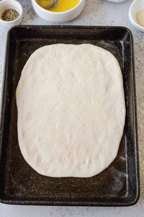 Soft pizza dough proofing on baking sheet for homemade pizza.
