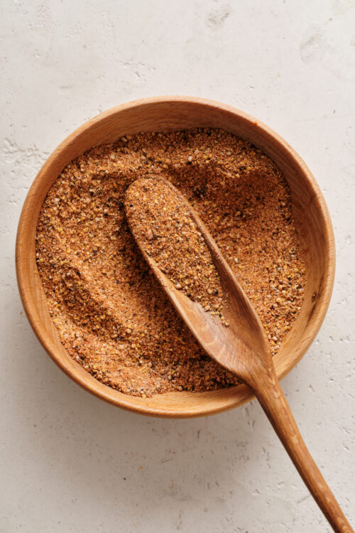 Ground spice blend in a wooden bowl with a scoop, perfect for baking and cooking.