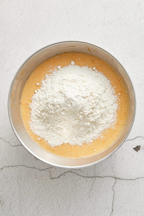 Flour being added to a bowl of cake batter for homemade baking.