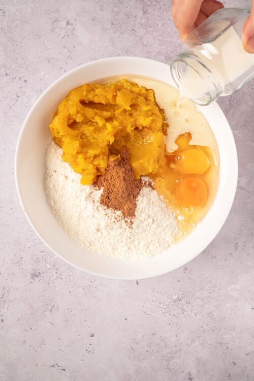Sweet potato pie filling ingredients in a white bowl, including mashed sweet potatoes, eggs, flour, spices, and milk.