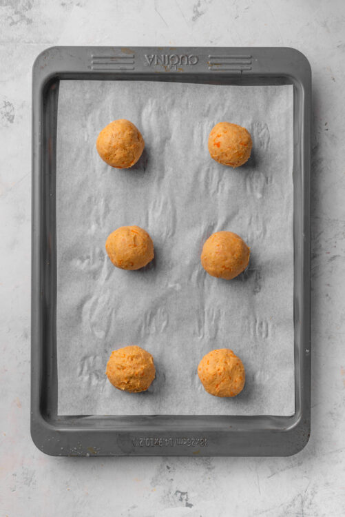 Baked cheese balls on parchment paper, ready for baking.