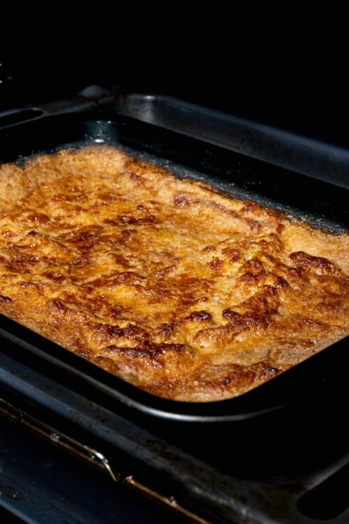 Crispy baked lasagna with golden cheese crust on oven tray.