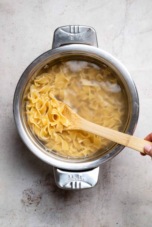 Cooked pasta boiling in a pot with steam rising.