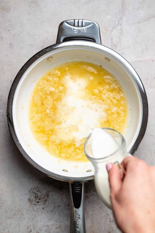 Cream being poured into a mixing bowl with butter and sugar, preparing ingredients for baking.