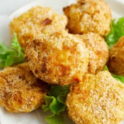 Crispy baked chicken nuggets on a white plate with lettuce, delicious homemade breaded chicken bites.