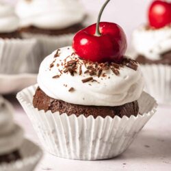 Cherry chocolate cupcake with frosting and chocolate shavings on top.
