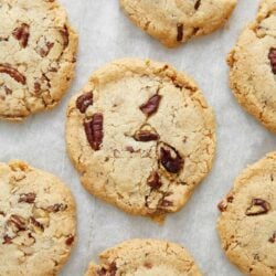 Butter pecan cookies with pecan pieces on parchment paper.