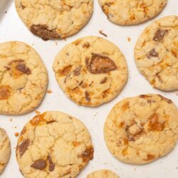 Buttery chocolate chip cookies with caramel bits on baking sheet.