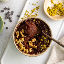 Decadent chocolate dessert with walnuts and yellow sprinkles on a white platter.