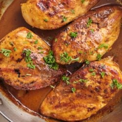 Juicy baked chicken thighs with a flavorful spice rub and fresh herbs in a skillet.