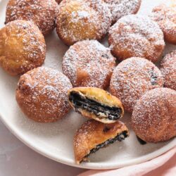 Oreo Stuffed Doughnuts with powdered sugar on a white plate.