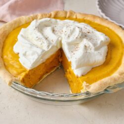 Rich pumpkin pie with whipped cream and a flaky crust, baked to perfection.