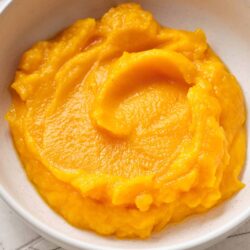 Creamy mashed sweet potatoes in a white bowl, perfect for Thanksgiving recipes.
